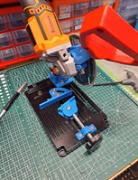 Customer unboxing the QuickMech angle grinder stand on wooden workbench next to a 12V cordless angle grinder and hardware bag ready for assembly